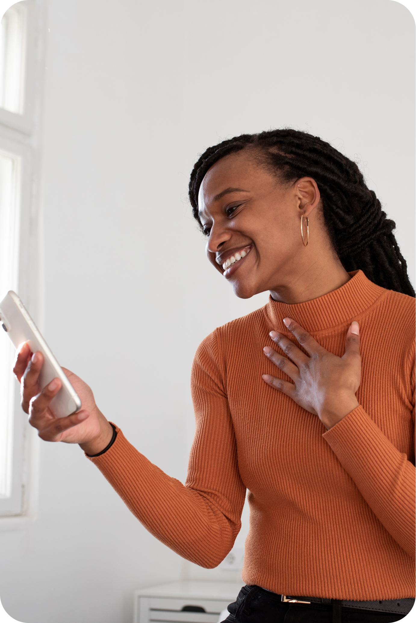image of a woman in an orange sweater smiling at her phone